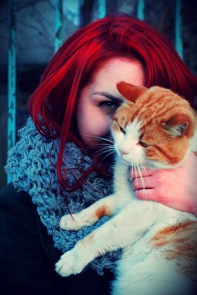 Chica con el pelo rojo con un gato en brazos